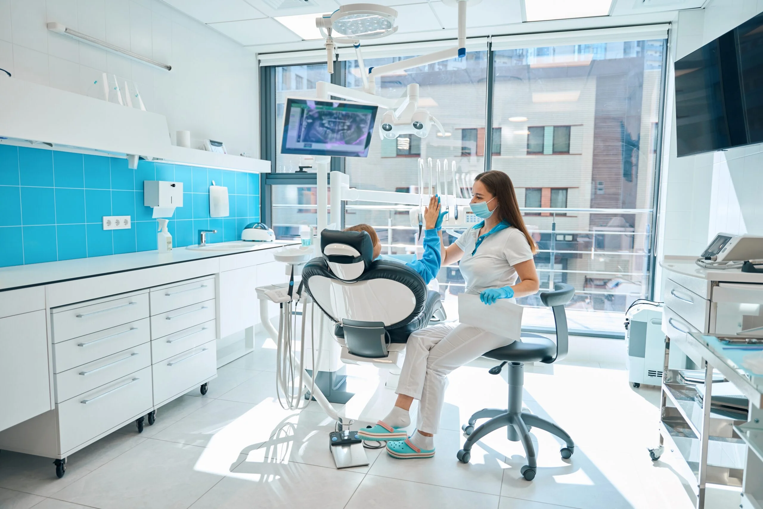 Dentist in a protective mask greets a girl at consultation