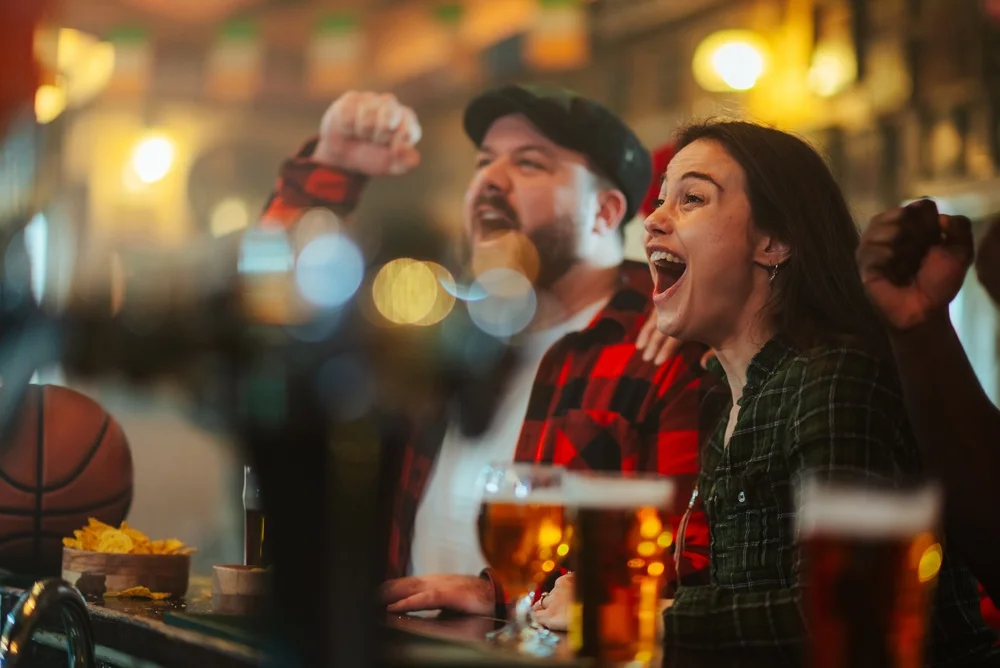 Group of excited sports fans watching a game in a pub