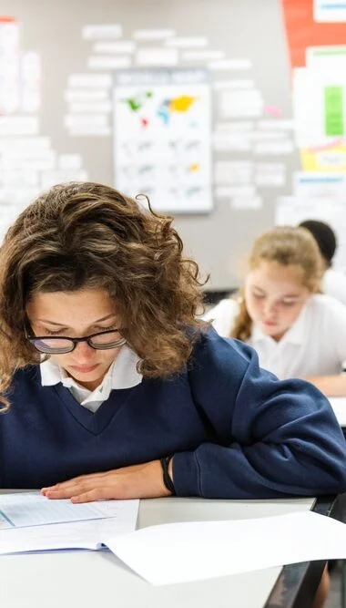 Students completing classroom assignments with a teacher, highlighting academic learning and student engagement for private school marketing.