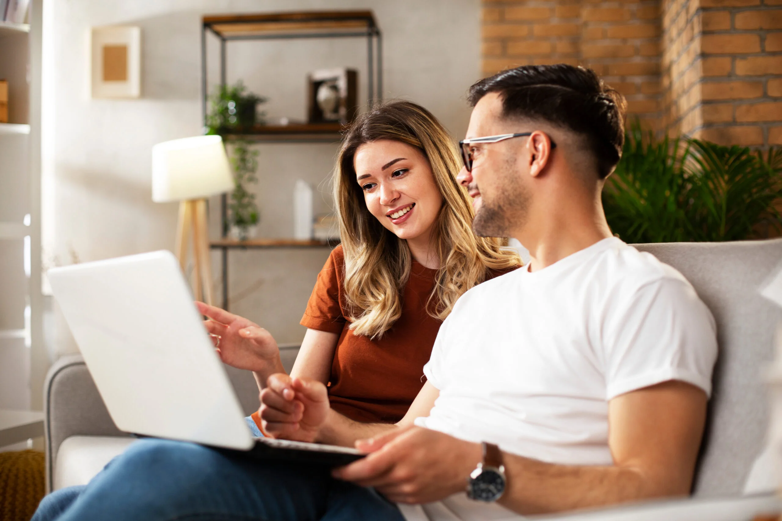 Couple browsing and shopping for furniture online together on a laptop at home.