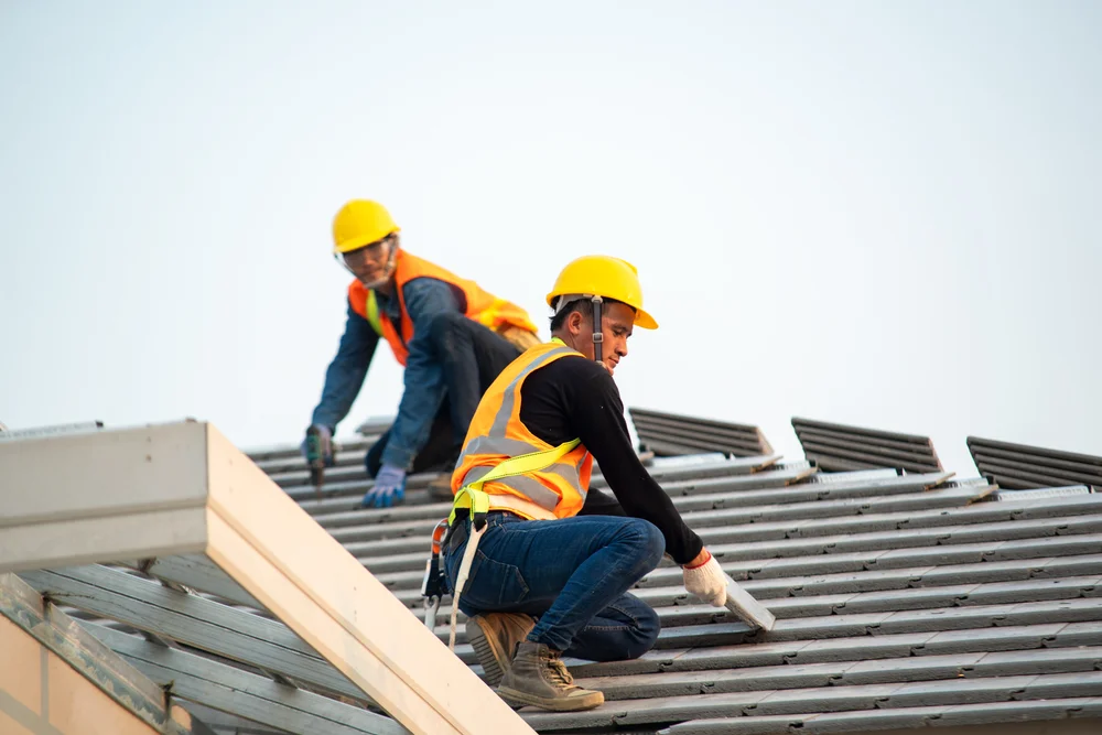 Roof repair construction worker using nail gun to install new roof