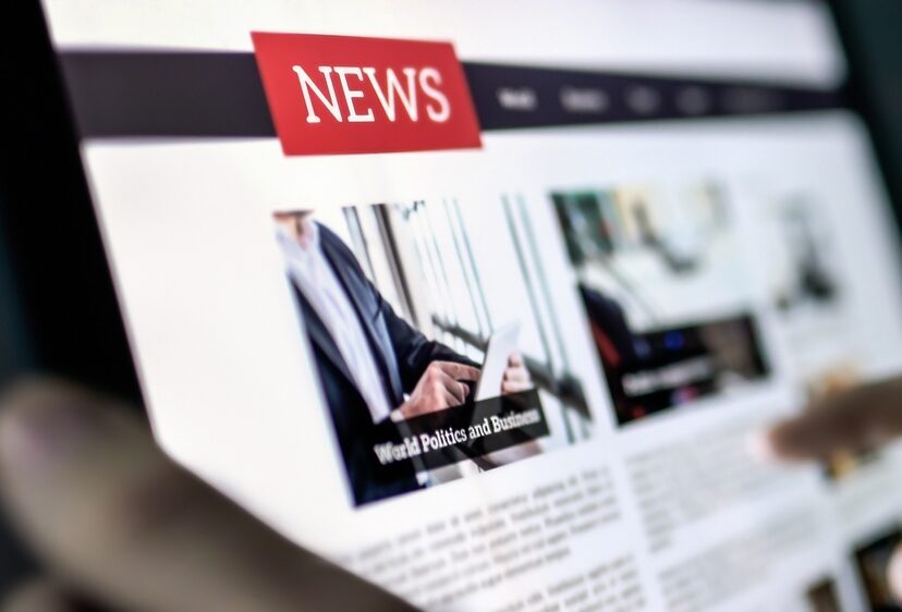 News press release in tablet reading newspaper article in tablet