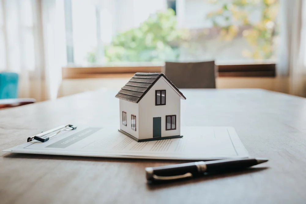 Miniature house model placed on real estate documents