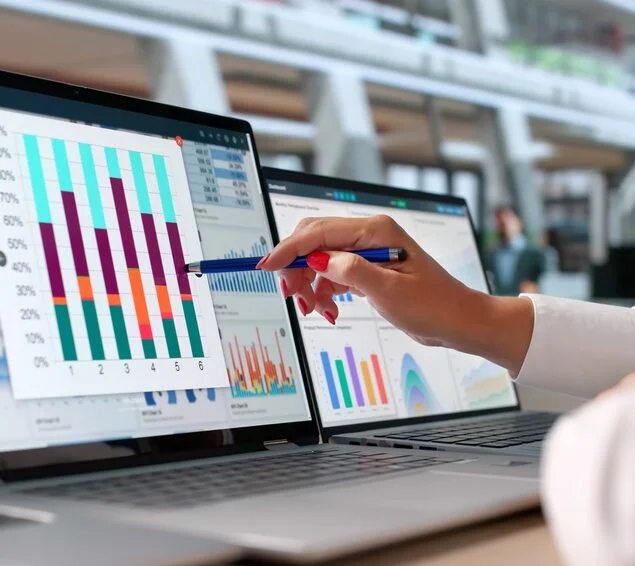 Marketing professional reviewing SaaS campaign performance, conversion data, and analytics dashboards across multiple computer screens.