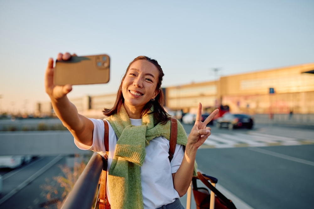 Happy woman smiling and making a peace sign taking a picture on Snapchat