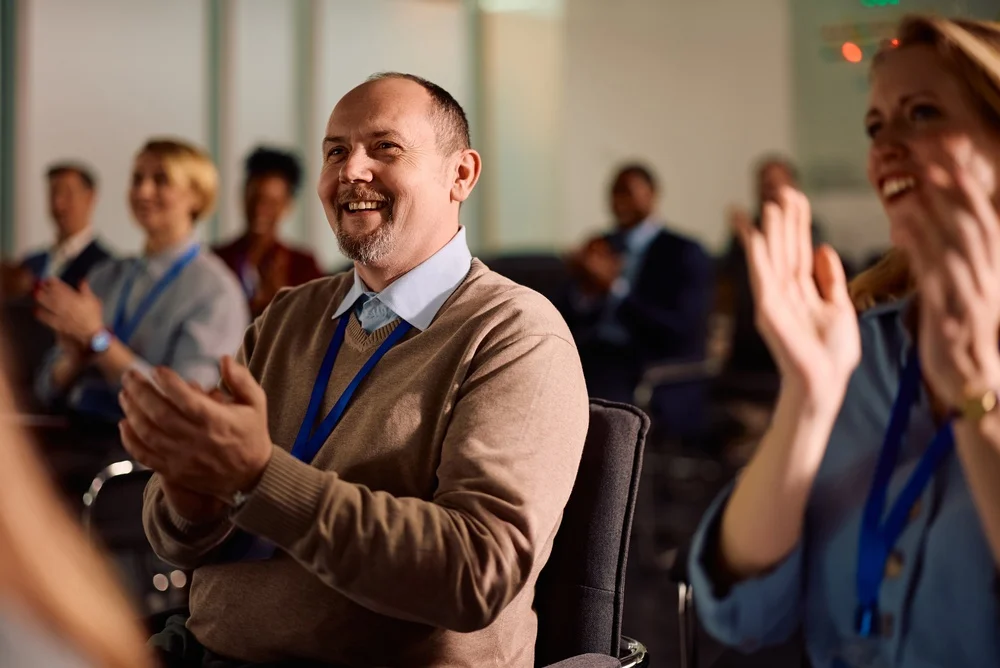 Happy entrepreneur and his coworkers applauding on business seminar
